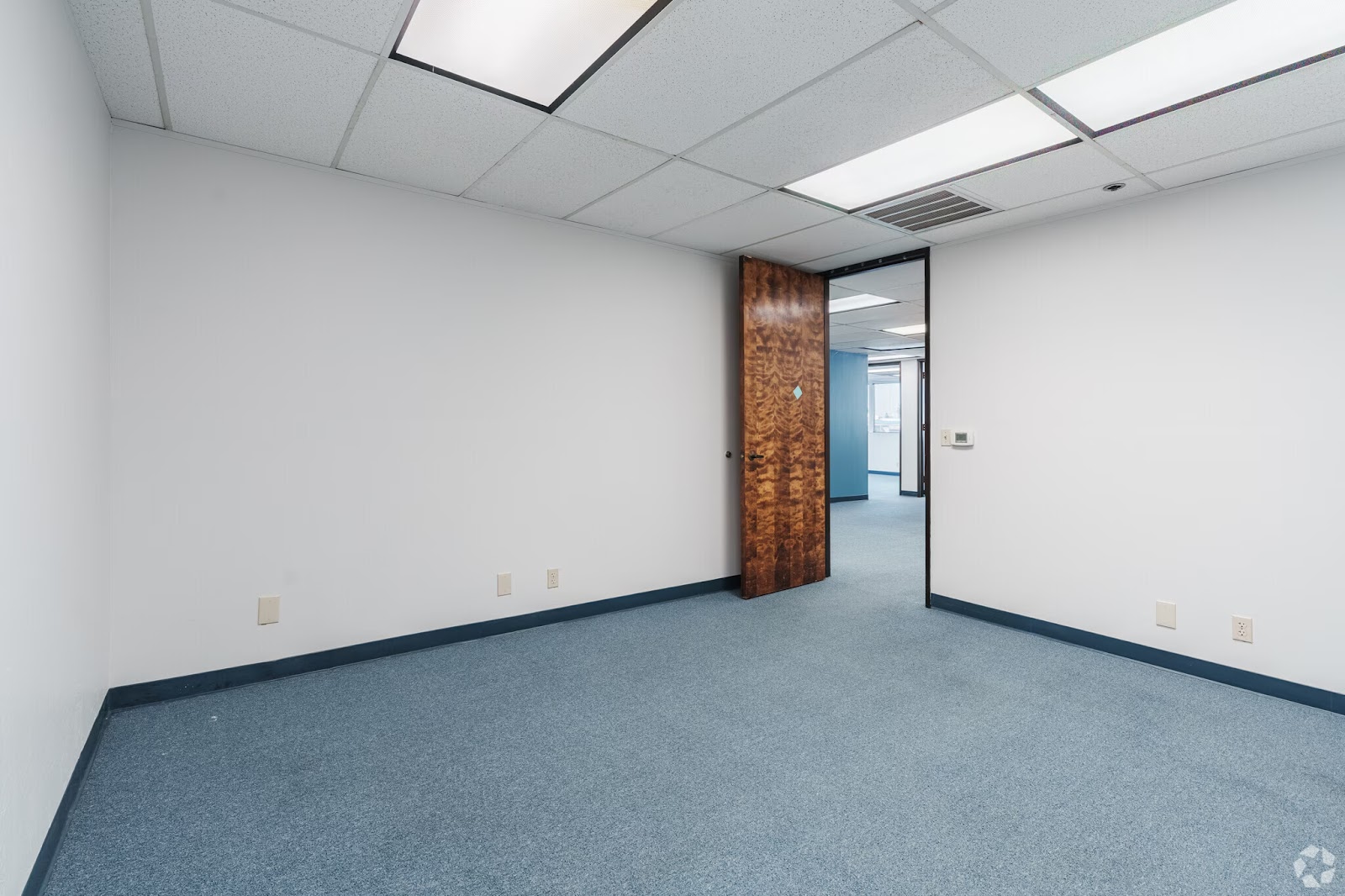 Private 150 SF professional office for lease at 200 New Stine Building in Bakersfield CA featuring a wood grain door and blue commercial carpeting.