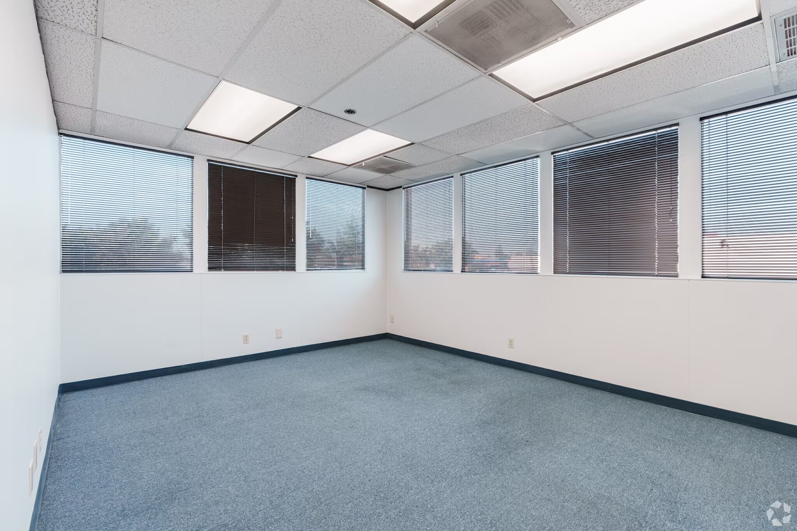 Large 350 SF corner office for lease at 200 New Stine Building in Bakersfield CA with multiple windows and blue commercial carpet.