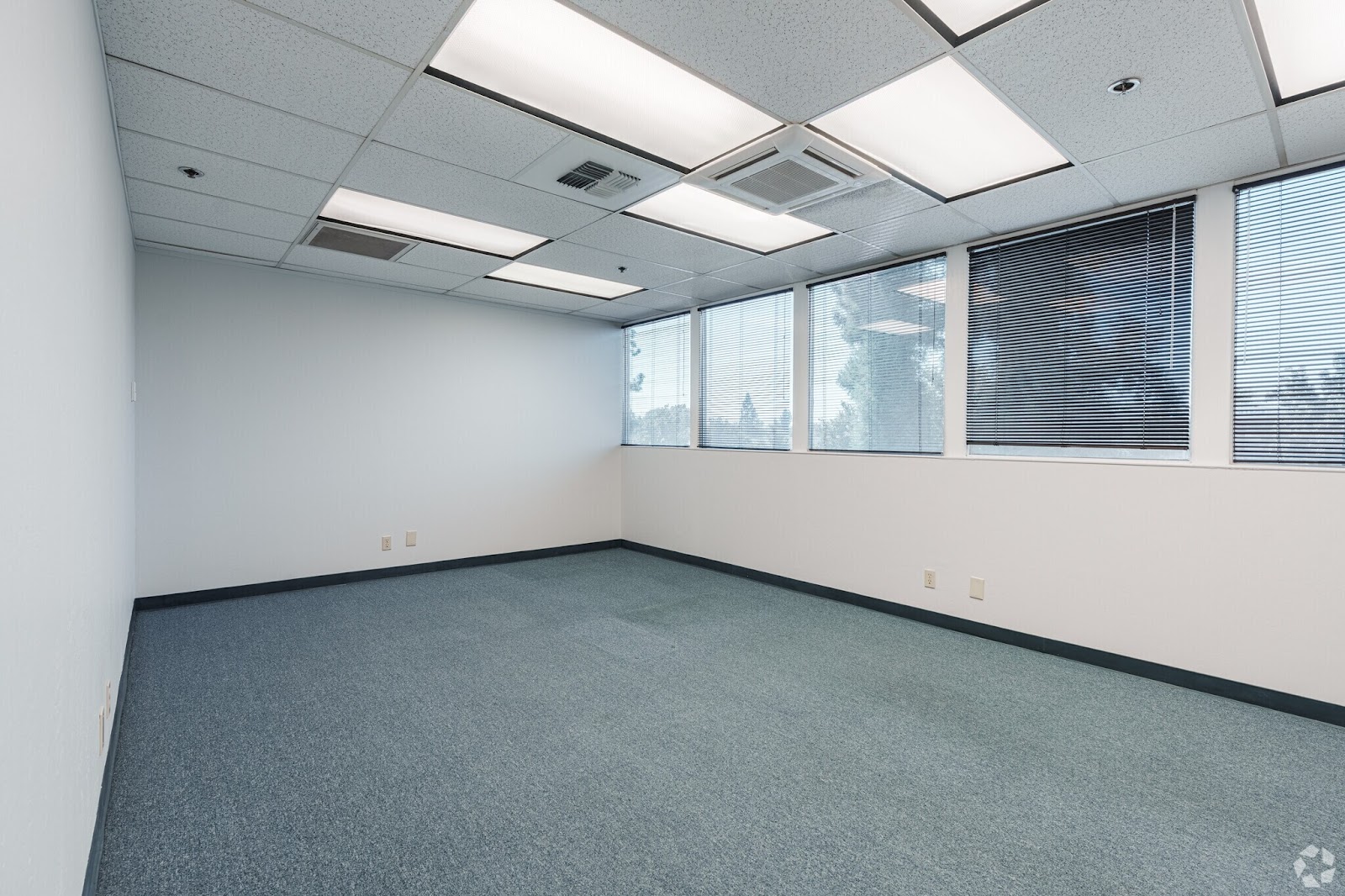 Private 250 SF office space for lease at 200 New Stine Building in Bakersfield CA featuring four large windows and blue commercial carpet.